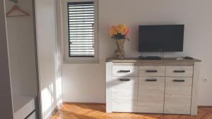 une chambre avec une télévision sur une commode avec un vase de fleurs dans l'établissement Apartment LIM, à Budva