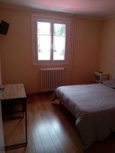 a bedroom with a bed and a window and a table at le rond gardien in Isle-et-Bardais