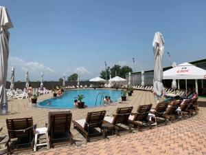 a pool with chairs and umbrellas and people sitting around it at Hotel Eden in Şimian