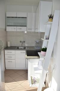 kuchnia z białymi szafkami i zlewem w obiekcie Apartmani Novosel w mieście Šilo