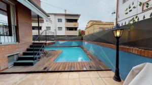 una piscina con terraza de madera y luz de la calle en HOUSE OF JOY , CASA EN BANYOLES, en Banyoles