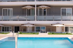 a hotel with a swimming pool and umbrellas at Astra Sarti Luxury Suites in Sarti