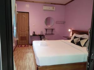 1 dormitorio con cama blanca y pared morada en Khao Sok Palm Garden Resort, en Khao Sok