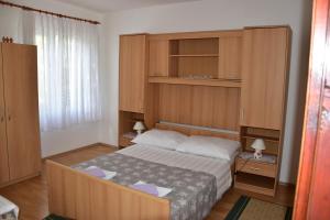 a small bedroom with a bed and wooden cabinets at Apartmani Novosel in Šilo
