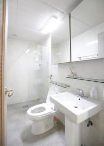 a white bathroom with a toilet and a sink at Lovely House Hongdae in Seoul