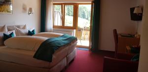 Schlafzimmer mit einem Bett vor einem Fenster in der Unterkunft Gasthaus Ratsstüble Garni in Simonswald