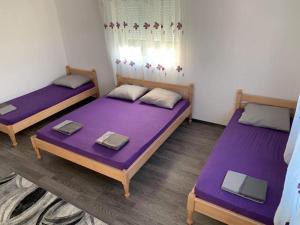 two beds in a room with purple sheets at Apartman Grande Ajna in Mostar