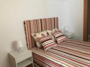 a bed with a striped headboard and pillows on it at Casa Dos Cabecinhos in Paradamonte