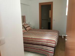 a bedroom with a bed with a striped blanket on it at Casa Dos Cabecinhos in Paradamonte