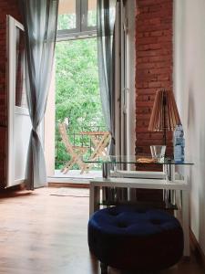 a glass table and a blue ottoman in front of a window at Topolove Rooms & Apartments in Krakow