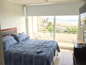 1 dormitorio con 1 cama con manta azul y balcón en Departamento Marserena frente al mar, en La Serena