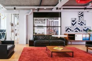 uma sala de estar com mobiliário de couro preto e um tapete vermelho em The Social Hub The Hague em Haia