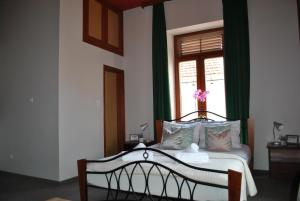 a bedroom with a bed with green curtains and a window at Vienna Story Guesthouse in Mostar