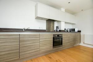 a kitchen with white appliances and wooden cabinets at Orion Marina Sea View - Parking - by Brighton Holiday Lets in Brighton & Hove