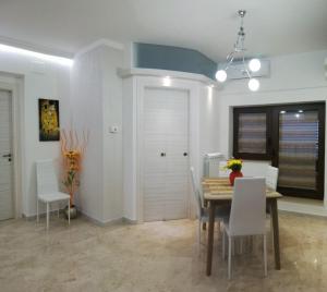 ein Esszimmer mit einem Tisch und weißen Stühlen in der Unterkunft Casa Vacanze LIBERTY in Licata