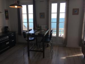 a dining room with a table and chairs and windows at Le Noroit in Étretat