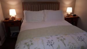 a bedroom with a bed with pillows and two lamps at Achintee Farm Guest House in Fort William