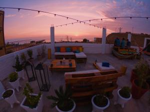 eine Dachterrasse mit Möbeln und Topfpflanzen bei Sonnenuntergang in der Unterkunft Los Faroles in Pacasmayo