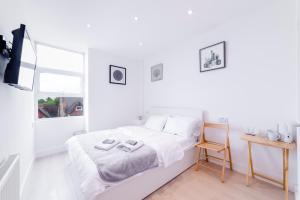 a white bedroom with a bed and a tv at Quiet cosy rooms in Harrow