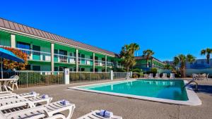 a swimming pool in front of a hotel with lounge chairs at Ramada by Wyndham Savannah Gateway in Savannah