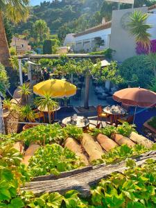 a garden with umbrellas and tables and chairs at Hôtel Beau Soleil in Le Lavandou