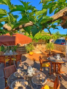 a patio with tables and chairs and an umbrella at Hôtel Beau Soleil in Le Lavandou