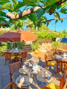 a patio with tables and chairs and an umbrella at Hôtel Beau Soleil in Le Lavandou