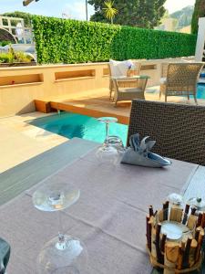a table with wine glasses on it next to a pool at Hôtel Beau Soleil in Le Lavandou
