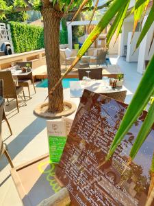 a table with a sign on it next to a tree at Hôtel Beau Soleil in Le Lavandou