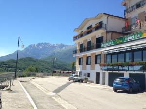 ein Auto, das vor einem Gebäude mit Bergen im Hintergrund parkt in der Unterkunft Hotel Pina Ristorante in Isola del Gran Sasso dʼItalia