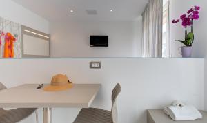 Cette chambre blanche dispose d'une table et d'un chapeau. dans l'établissement Alloggio Nella, à Rimini