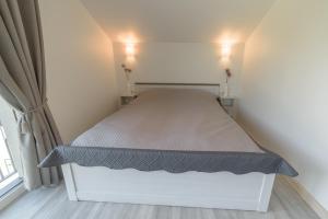 - un lit blanc dans une chambre avec deux lumières allumées dans l'établissement Gerves Apartamentai, à Palanga