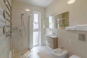 a white bathroom with a shower and a sink at Gerves Apartamentai in Palanga