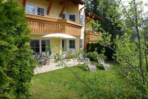 a house with a patio and an umbrella in the yard at Haus Elisengrund am Geigenbuehel - chalet privé in Seefeld in Tirol