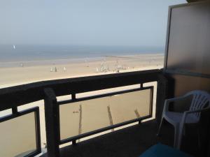 a balcony with a view of a beach and a chair at Residentie Aldis met zeezicht in Ostend