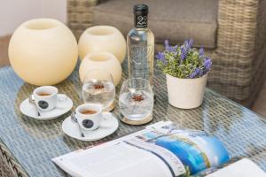 a glass table with two cups of coffee and a bottle at Boutique Hotel Oriola in Cala de Sant Vicenc