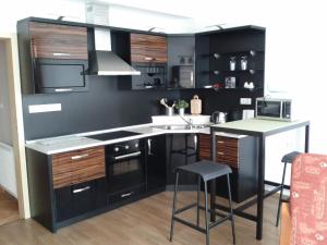 a kitchen with black cabinets and a kitchen island with a microwave at Apartmán Residence Nábřeží in Beroun