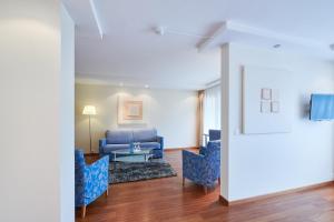 ein Wohnzimmer mit einem blauen Sofa und Stühlen in der Unterkunft Hotel Holiday Thun in Thun