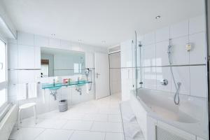 biała łazienka z wanną i umywalką w obiekcie Hotel Holiday Thun w mieście Thun
