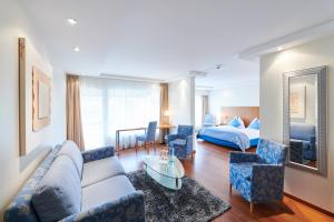 a living room with a couch and chairs and a bed at Hotel Holiday Thun in Thun +41 photos