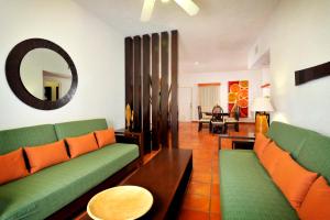 a living room with two green couches and a mirror at Las Palmas Condominio in Playa del Carmen