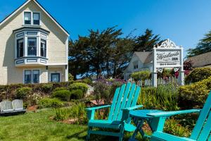 two blue chairs sitting in the grass in front of a house at Headlands Inn Bed and Breakfast in Mendocino