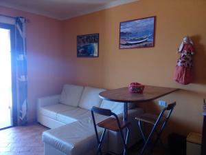 ein Wohnzimmer mit einem Tisch und einem Sofa in der Unterkunft SEA VIEW HOUSE SARDEGNA in Badesi
