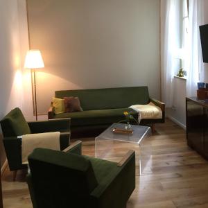 a living room with a green couch and a table at Ferienwohnung Kamp `Himmelsblick` mit Schlafgalerie in Potsdam