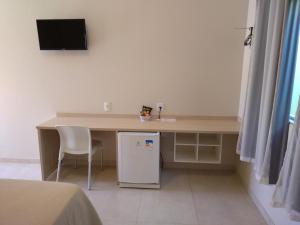 a desk with a small refrigerator and a television on a wall at Hotel Portal do Corrente in Santa Maria da Vitória