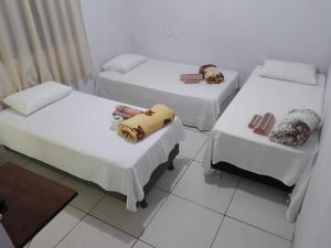 three beds in a room with white walls at Pousada Mãe e Filhas in Mateiros