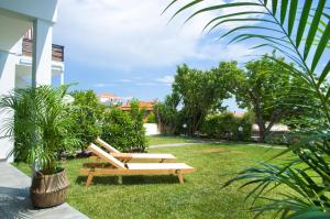 two benches sitting in the grass near a building at Thea Suites Potidea in Nea Potidaea