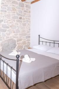 a bedroom with a bed with a stone wall at Apartmani Španja in Vodice