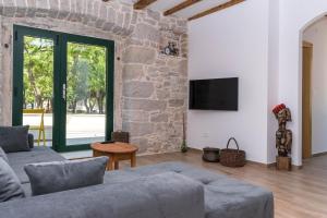 a living room with a couch and a stone wall at Apartmani Španja in Vodice
