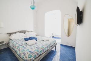1 dormitorio con 1 cama con espejo y azulejos azules en La Pignatara Capri, en Capri